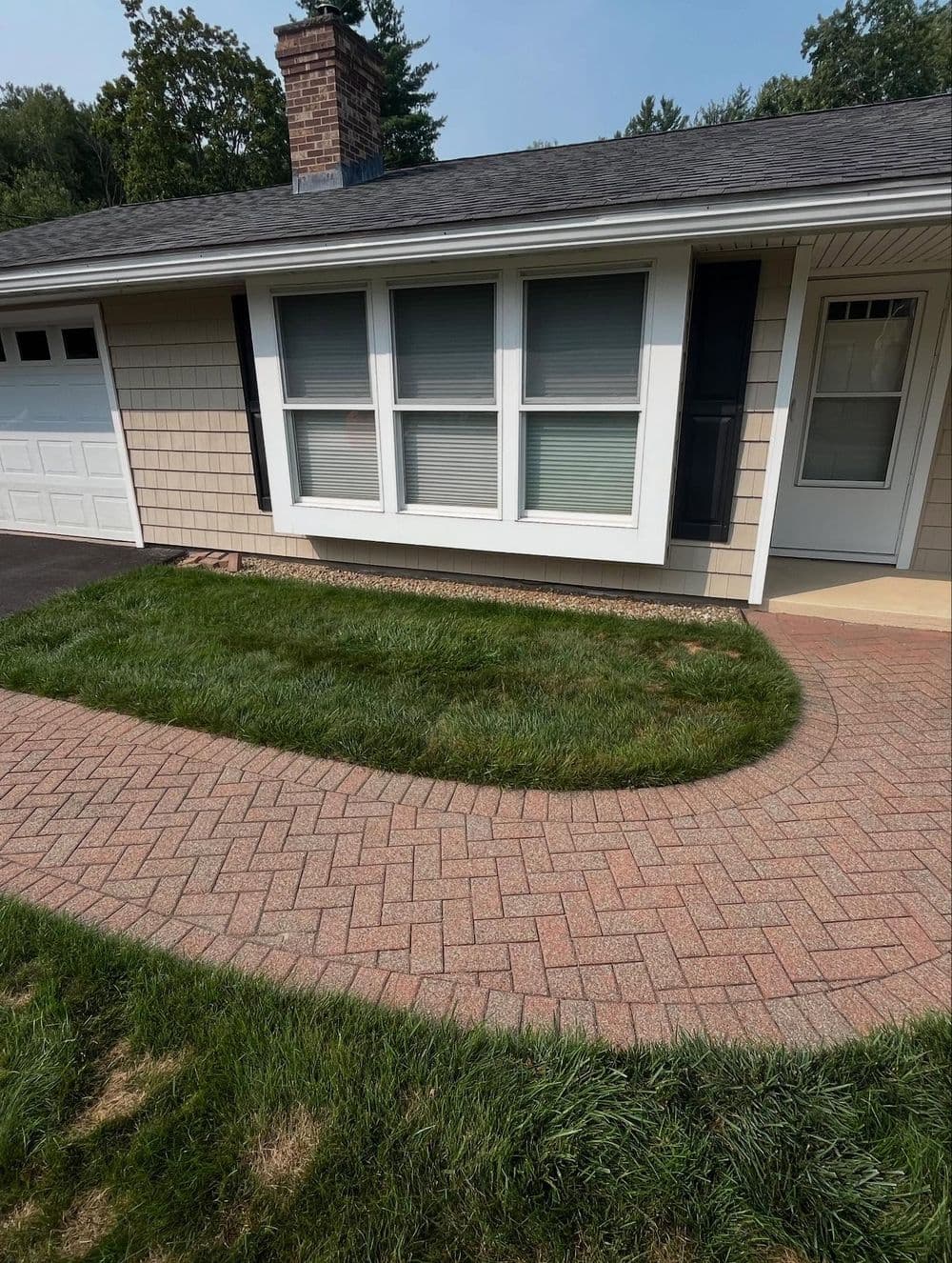 Front exterior of a house featuring a landscaped lawn and paved walkway.